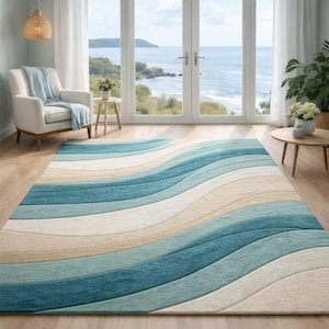 Op de afbeelding: Een groot rechthoekig vloerkleed met een golfpatroon in tinten blauw, turquoise en beige. Het kleed ligt op een houten vloer. Het ontwerp roept de oceaan op, met kleuren die de zee en het zand nabootsen.