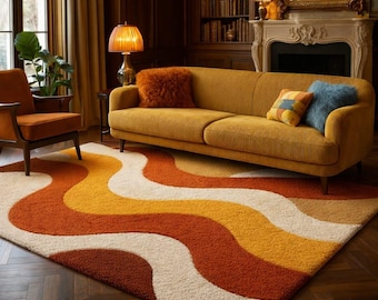 May include: A living room scene featuring a mustard yellow corduroy sofa with decorative pillows, a matching armchair, and a retro-style rug. The rug has a wavy pattern in shades of orange, yellow, and cream. A fireplace and bookshelves are in the background.
