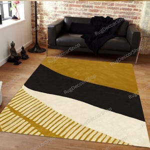 Könnte beinhalten: Ein moderner Teppich mit geometrischem Design. Der Teppich hat ein Farbschema aus Senfgelb, Schwarz und Off-White. Ein Teil des Teppichs hat ein Muster aus parallelen Linien. Der Teppich liegt auf einem Holzboden.