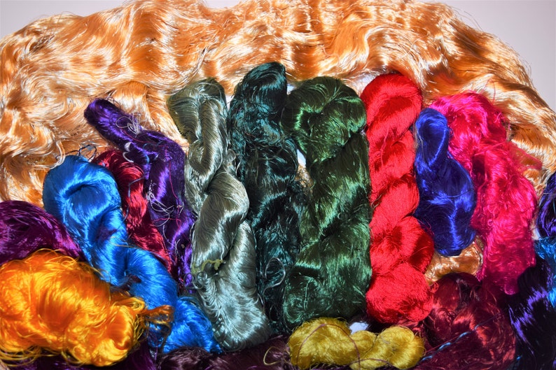 May include: A collection of colorful silk threads in various shades of green, blue, red, purple, and orange. The threads are arranged in a semi-circle, with the orange threads at the top.