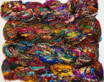 May include: A skein of colorful silk yarn with a variety of textures and shades of blue, green, purple, red, gold, and black.