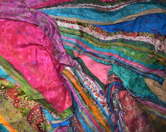 May include: A vibrant textile featuring a patchwork design of various fabrics. The colors include shades of pink, blue, green, and orange. The fabric appears to be layered, creating a textured and visually rich composition.