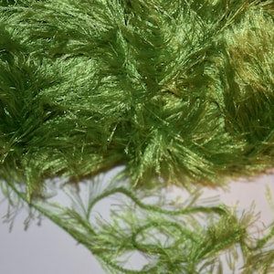 May include: A skein of bright green fuzzy yarn with long strands. The yarn is soft and fluffy, perfect for knitting or crocheting.