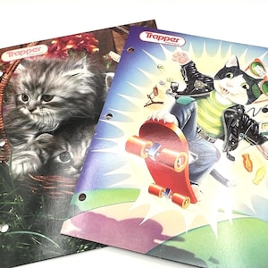 May include: Two Trapper portfolio binders. One features a fluffy gray kitten in a basket. The other shows a cat in a leather jacket riding a skateboard. Both binders have the Trapper logo.