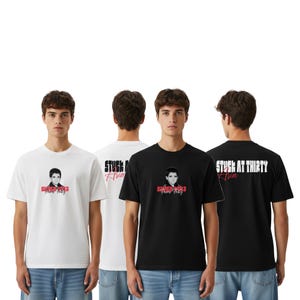 May include: White and black t-shirts with the text "STUCK AT THIRTY Ava" in red and white. The shirts feature a graphic of a person. The t-shirts are short-sleeved and are being modelled.