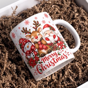 Puede incluir: Una taza de cerámica blanca con una ilustración colorida de un muñeco de nieve, un reno y Santa Claus rodeados de flores de pascua rojas y copos de nieve. El texto Merry Christmas está impreso en letra roja debajo de los personajes.