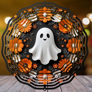 Op de afbeelding: Een ronde wanddecoratie met een centrale witte spookfiguur omringd door een gelaagde krans van oranje en witte bloemen, donkergrijs gebladerte en zwarte geschulpte randen, wat een meerdimensionaal effect van gelaagd papier creëert.