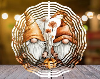 Peut inclure: Découpe décorative en métal représentant deux gnomes avec des chapeaux orange et de longues barbes blanches. Ils sont entourés de fleurs et d'une petite citrouille. La découpe a un design ondulé et superposé avec une finition dorée.