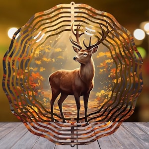 Peut inclure: Un cerf brun avec de grands bois se tient dans une scène de forêt, encadré par une découpe métallique décorative et superposée. La découpe a un design ondulé et circulaire avec une boucle de suspension en haut. L'arrière-plan présente un feuillage d'automne.