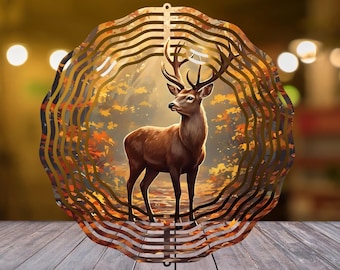 Peut inclure: Un cerf brun avec de grands bois se tient dans une scène de forêt, encadré par une découpe métallique décorative et superposée. La découpe a un design ondulé et circulaire avec une boucle de suspension en haut. L'arrière-plan présente un feuillage d'automne.