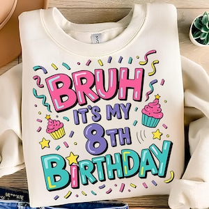 以下が含まれることがあります： クリーム色のスウェットシャツ。カラフルな文字で「BRUH IT'S MY 8TH BIRTHDAY」と書かれています。カップケーキ、星、紙吹雪のデザイン。楽しくお祝いの誕生日をテーマにしたアパレルアイテムです。
