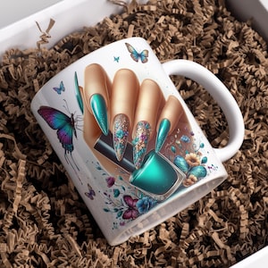 Op de afbeelding: Witte keramische mok met een hand met lange, teal-gekleurde nagels en een teal-kleurige nagellakfles. De mok is versierd met vlinders en bloemmotieven. De mok wordt gepresenteerd in een witte doos gevuld met bruin papier.