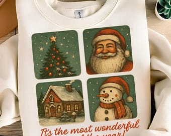 Op de afbeelding: Witte sweatshirt met vier vierkante afbeeldingen: een kerstboom, de kerstman, een huis en een sneeuwpop. De tekst "It's the most wonderful time of the year!" is in rood script gedrukt. Een feestelijk vakantieartikel.
