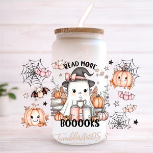 Puede incluir: Un vaso de vidrio esmerilado con tapa de bambú y pajita transparente, con un gráfico de un fantasma con sombrero de bruja, rodeado de calabazas, murciélagos, telarañas y libros, con el texto "READ MORE BOOOOKS" impreso en letras negras.