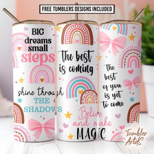 Puede incluir: Vaso blanco con diseños de arcoíris, lazos y estrellas. El texto incluye "Big dreams small steps", "The best is coming" y "Believe and make magic". Incluye una pajita y el texto "Free Tumblers Designs Included".