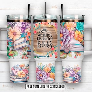 Puede incluir: Tres vasos blancos de 1,18 litros con diseños florales y pajitas negras. El vaso central presenta el texto "Easily Distracted by Books" sobre un fondo de madera. Cada vaso tiene un arreglo floral diferente.