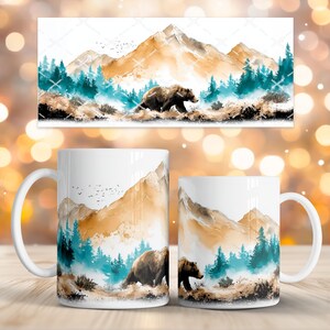 May include: White ceramic coffee mugs with a watercolour design of a brown bear in a mountain landscape. The design includes teal trees, brown mountains, and a white background. The mugs have a standard handle and a glossy finish.
