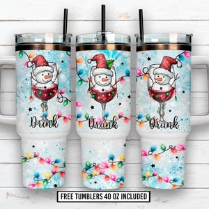 Puede incluir: Tres vasos de 1,18 litros con temática invernal. Cada vaso presenta un muñeco de nieve en una copa de vino, con un gorro de Papá Noel, con la palabra "Drink" debajo. El fondo es azul claro con copos de nieve y luces de colores.