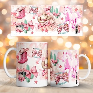 Puede incluir: Taza de cerámica blanca con un tema de vaquera rosa y marrón. El diseño incluye un sombrero de vaquero, botas, lazos, cactus, estrellas y un caballo rosa. El texto incluye "Cowgirl", "Wildwest Cowgirl" y "Dibs on the Cowboy".