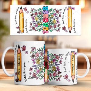 May include: White ceramic mug with a colorful floral design and the word "TEACHER" in rainbow letters. The mug also features a yellow pencil graphic and the text "Teach them, love them. Watch them grow."
