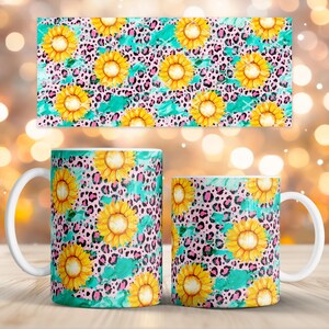 Puede incluir: Dos tazas de café con asa blanca y un objeto rectangular presentan un patrón repetido de girasoles amarillos, manchas de leopardo rosas y pinceladas turquesas. Las tazas son cilíndricas, y el objeto rectangular es probablemente un posavasos o un mantel individual.
