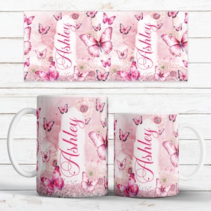 May include: Pink and white ceramic mug and matching rectangular coaster, both featuring a butterfly and floral design. The name "Ashley" is printed vertically on both items. The mug has a white handle and a glittery base.