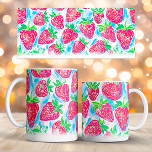 Puede incluir: Dos tazas de cerámica blanca con un vibrante estampado de fresas. El diseño presenta fresas de color rosa brillante con hojas verdes sobre un fondo azul claro y blanco. Una impresión rectangular a juego está encima de las tazas.
