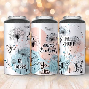 Puede incluir: Tres vasos aislados blancos con tapas negras, cada uno con un diseño único. Uno tiene una abeja y las palabras "Be Happy", otro dice "Always Bee-lieve, You matter", y el último dice "Shine Bright, Enjoy the little things". Acentos florales y de diente de león.