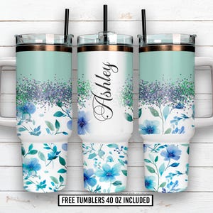 Puede incluir: Tres vasos de 1,18 litros con tapas y pajitas. Los vasos presentan un diseño turquesa y blanco con motivos florales azules y el nombre "Ashley" en cursiva. El diseño incluye detalles de purpurina.