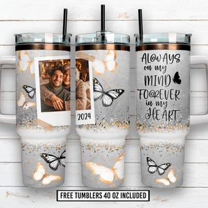 Puede incluir: Tres vasos de 1,18 litros con tapas y pajitas. Los vasos tienen un fondo gris con diseños de mariposas y purpurina. Un vaso tiene una foto y el año 2024. Otro vaso tiene el texto "Always on my mind, forever in my heart."