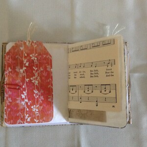 Puede incluir: Un peque&ntilde;o libro hecho a mano con una etiqueta de patr&oacute;n floral rojo y blanco unida a la portada. El libro est&aacute; abierto en una p&aacute;gina con partitura musical que presenta la letra "Sweet Allot, Ben Bolt, the wood, Ben Bolt, the school, Ben Bolt, Near the And the (3)"
