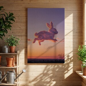May include: A canvas print depicts a cloud formation shaped like a rabbit leaping across a sunset sky. The artwork features warm orange and pink hues at the horizon, transitioning to purple above. The rabbit cloud is detailed with shadows, creating a whimsical and artistic scene.