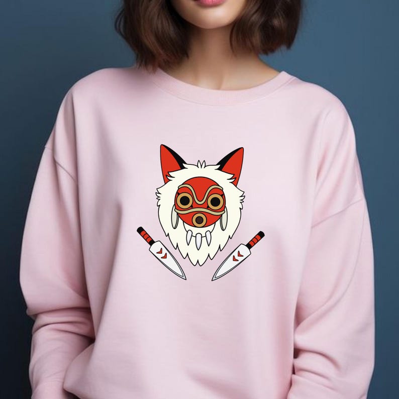 May include: A pale pink sweatshirt with a graphic of a red and white mask and two knives. The mask has a fox-like design with red ears and a white fur-like outline. The knives are silver with red and black handles.