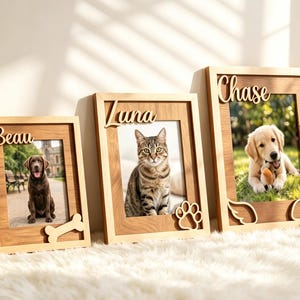 Könnte beinhalten: Drei rechteckige Bilderrahmen aus Holz mit den Namen Beau, Luna und Chase in Schreibschrift. Die Rahmen zeigen Fotos eines braunen Hundes, einer getigerten Katze und eines Golden Retriever Welpen, verziert mit Holzausschnitten in Knochen-, Pfoten- und Flügelform.