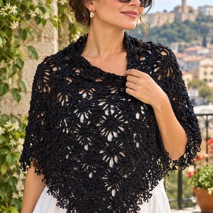 May include: A black triangular shawl featuring an intricate crochet pattern with repeating floral motifs and a delicate scalloped edge. The garment is constructed from fine yarn, showcasing a detailed openwork design that drapes over the shoulders.