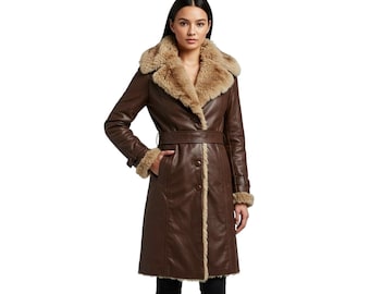 May include: A long, brown leather coat with a faux fur collar and trim. The coat features a belted waist, button closure, and pockets. The model is wearing black pants.
