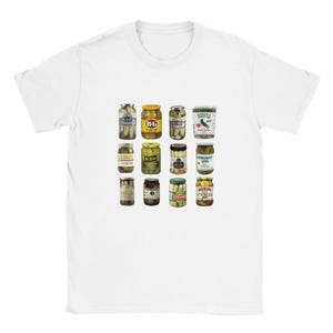 Op de afbeelding: Wit T-shirt met een raster van twaalf potten augurken met verschillende etiketten. De potten zijn gevuld met augurken van verschillende soorten en maten. Het shirt heeft een klassieke ronde hals.