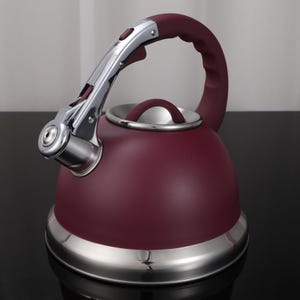 May include: A burgundy-colored stovetop kettle with a stainless steel base and accents. The kettle features a large, arched handle and a small, rounded spout. The handle and lid are burgundy, while the spout and base are silver.