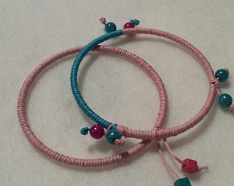 Set of two bangles. Pink and turquoise cord wrapped. Accented with miracle beads and square wood beads. FREE SHIPPING!