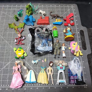 May include: A white ceramic mug with a black handle and the text "But First, Coffee" in a bold, black font. The mug is set against a blurred background, suggesting a cozy setting.