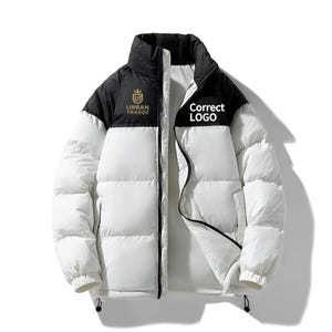 May include: A white and black puffer jacket with a high collar and a full-length zipper. The jacket features the text "URBAN TRAEDZ" and "Correct LOGO" on the chest. The jacket is designed for warmth and protection from the elements.