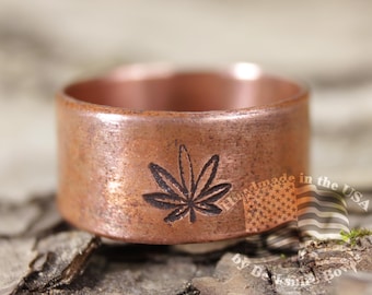 以下が含まれることがあります： 大麻の葉のデザインが施された銅製のリング。リングは幅広のバンドと素朴な仕上がりです。大麻の葉は銅にエッチングされています。アメリカ製。
