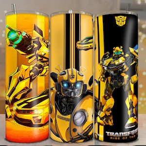 May include: A cylindrical tumbler featuring yellow and black graphics of the character Bumblebee from Transformers. The design includes a yellow sports car, a robot in action, and the text Transformers Rise of the Beasts with a logo.
