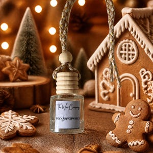 May include: A small, clear glass bottle with a light-coloured wooden cap and a braided hanging cord. The label features the text The Wax Company and Gingerbread. The bottle is positioned upright, showcasing its simple, functional design.
