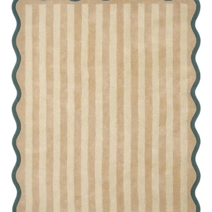 May include: A rectangular rug featuring a pattern of vertical stripes in alternating shades of tan and cream. The rug is finished with a dark teal scalloped border that follows the wavy edge of the entire perimeter of the textile piece.
