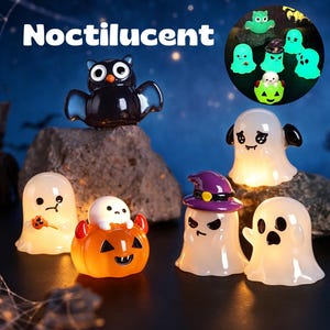 Könnte beinhalten: Eine Sammlung kleiner, nachtleuchtender Halloween-Figuren, darunter eine schwarze Eule, mehrere weiße Geister mit verschiedenen Gesichtsausdrücken und ein weißes Wesen, das in einem orangefarbenen Kürbis mit roten Teufelshörnern sitzt.