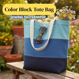 May include: A color block tote bag with a light blue, medium blue, and navy blue design. The bag has cream-colored handles and a pair of sunglasses hanging from the top. The bag is filled with flowers. Text on the image reads "Color Block Tote Bag" and "Sewing Pattern PDF".