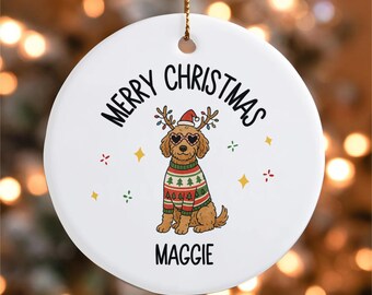 Peut inclure: Ornement de Noël rond en céramique blanche avec un chien de dessin animé portant un bonnet de Père Noël, des lunettes de soleil en forme de cœur et un pull de Noël. Le texte dit "MERRY CHRISTMAS" et "MAGGIE". Comprend une ficelle dorée.