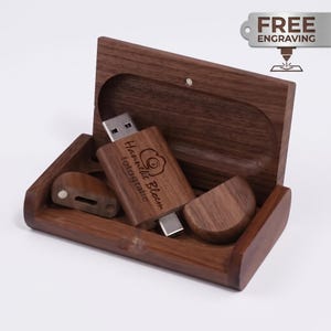 Puede incluir: Una memoria USB de madera marrón oscuro con su caja de almacenamiento rectangular a juego. La memoria USB presenta el texto grabado Hannelie Blom fotografie y un icono de cámara. Una etiqueta plateada muestra el texto FREE ENGRAVING.
