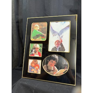 May include: A black multi-opening picture frame with a thin gold metal border. The frame features five distinct openings: three square openings, one large vertical rectangular opening, and one large horizontal oval opening, all containing photos.
